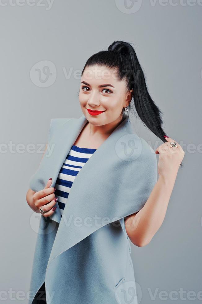 portrait en studio de jeune femme au manteau avec des lèvres rouges photo