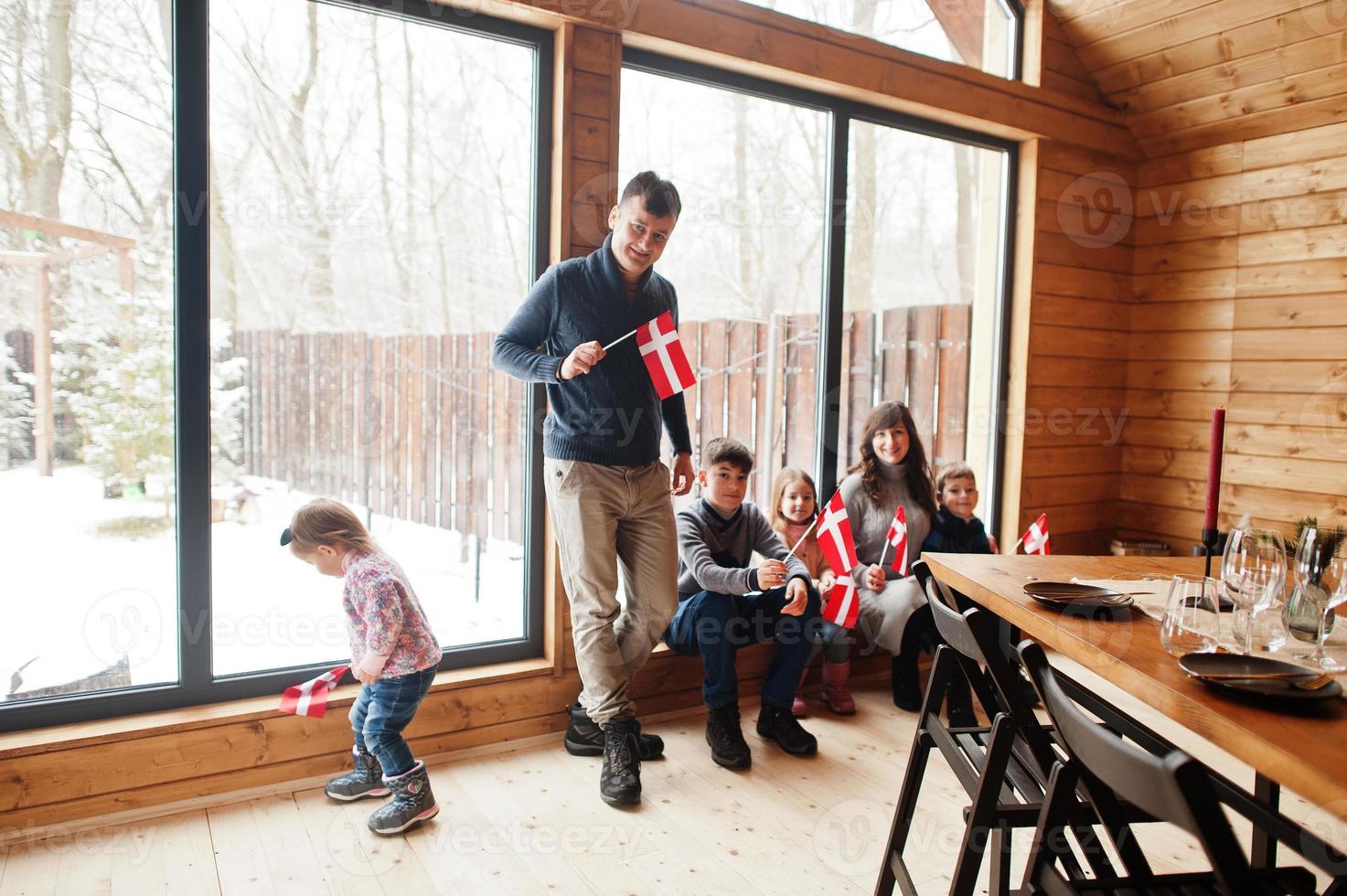 famille avec des drapeaux du danemark à l'intérieur de la maison en bois. voyage dans les pays scandinaves. les danois les plus heureux. photo