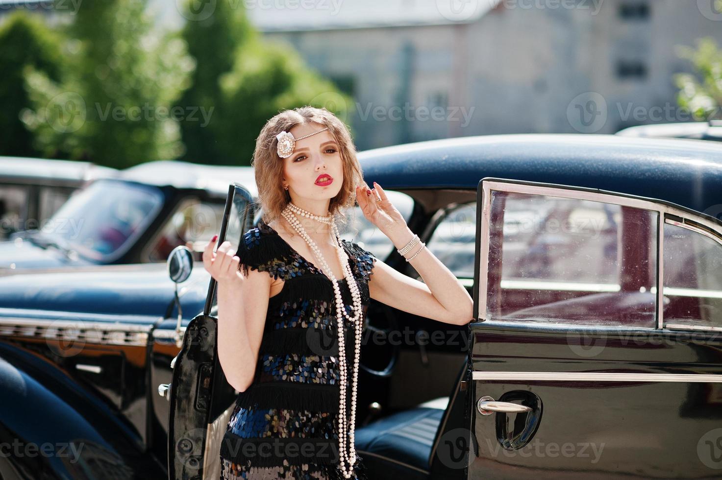 portrait de beau modèle de fille de mode bouclée sexy avec un maquillage lumineux dans un style rétro près d'une voiture vintage photo