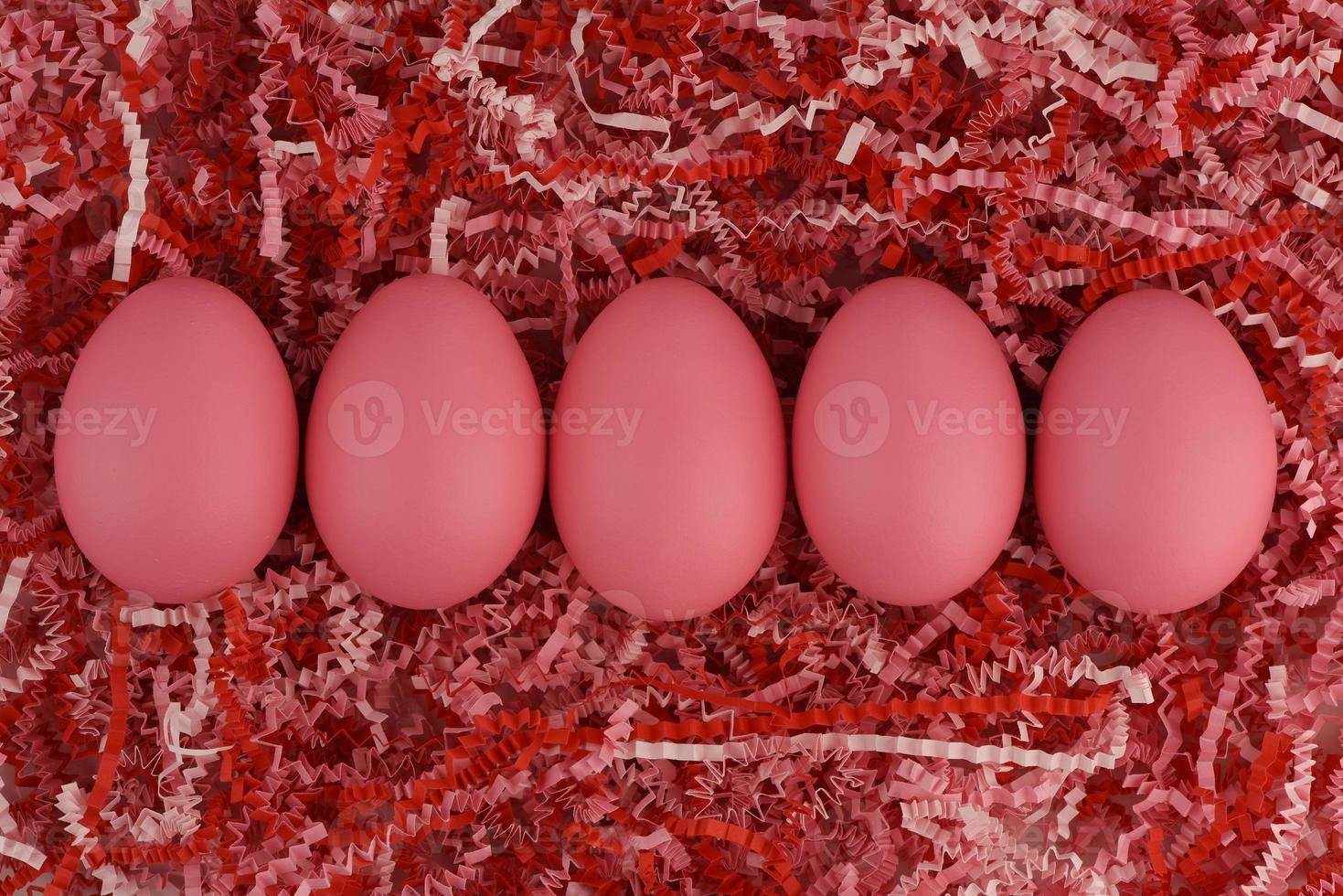 cinq oeufs de pâques roses d'affilée sur du papier rayé dans des tons rouges et roses photo