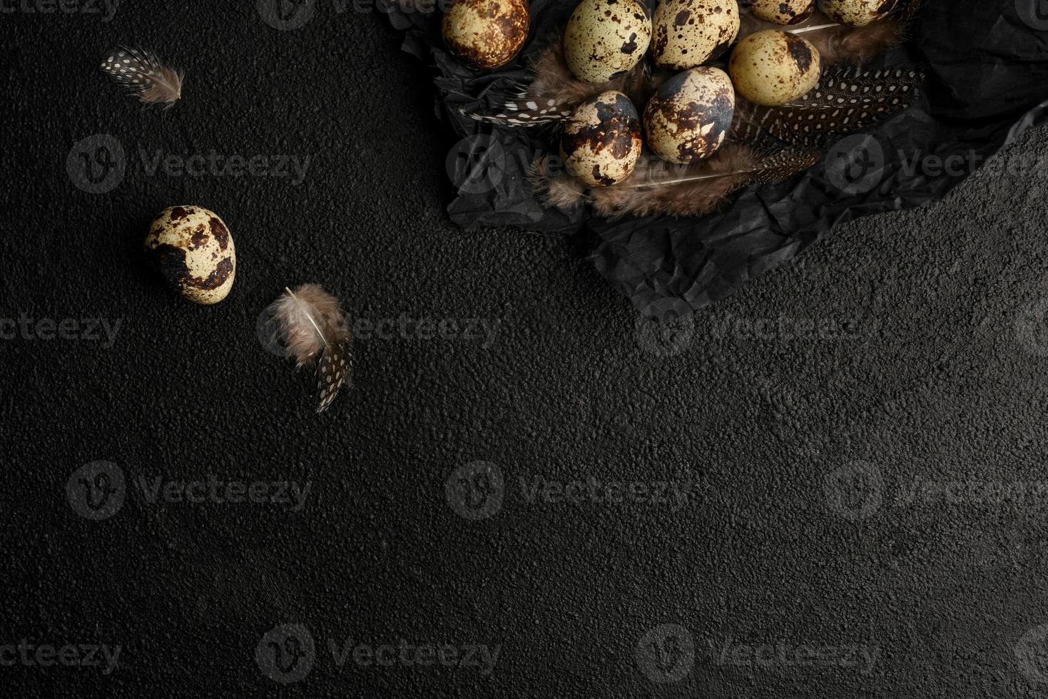 oeufs de caille et plumes sur papier d'emballage froissé noir. photo