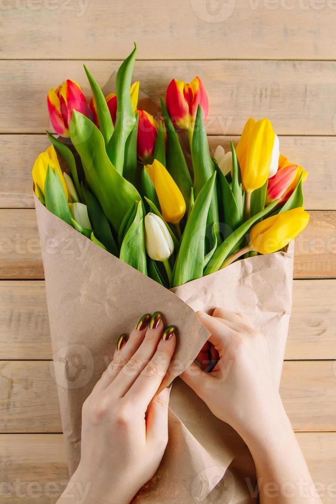 le processus d'emballage d'un bouquet de tulipes fraîches dans du papier kraft écologique photo