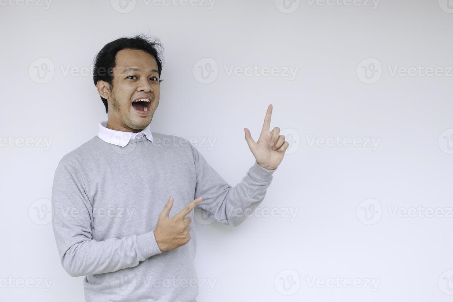 jeune homme asiatique est souriant et heureux avec le point de la main sur l'espace vide photo