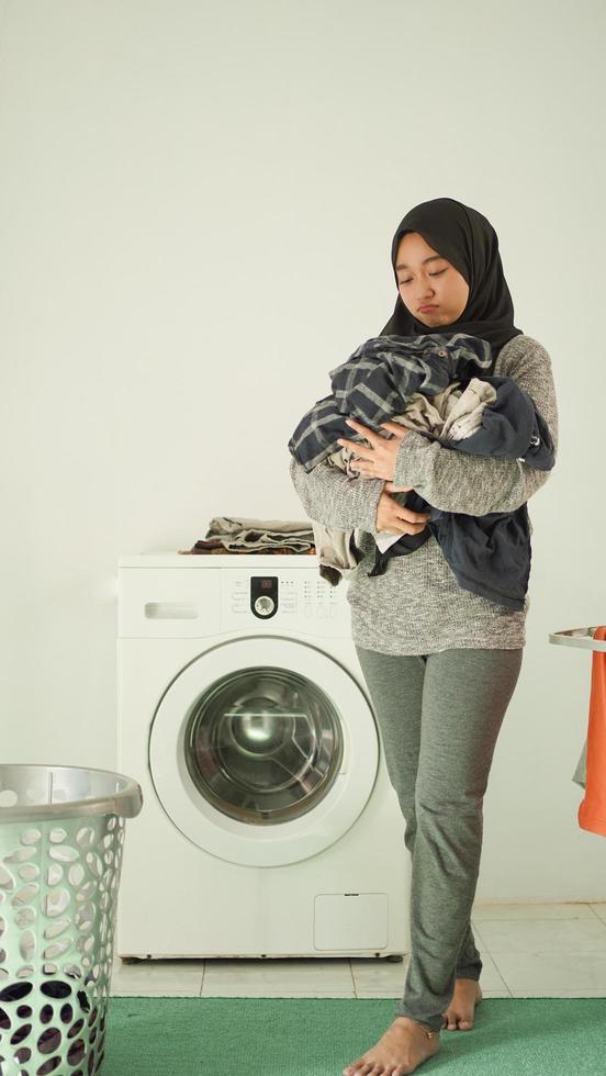 femme asiatique en hijab apporte sa lessive à la maison photo