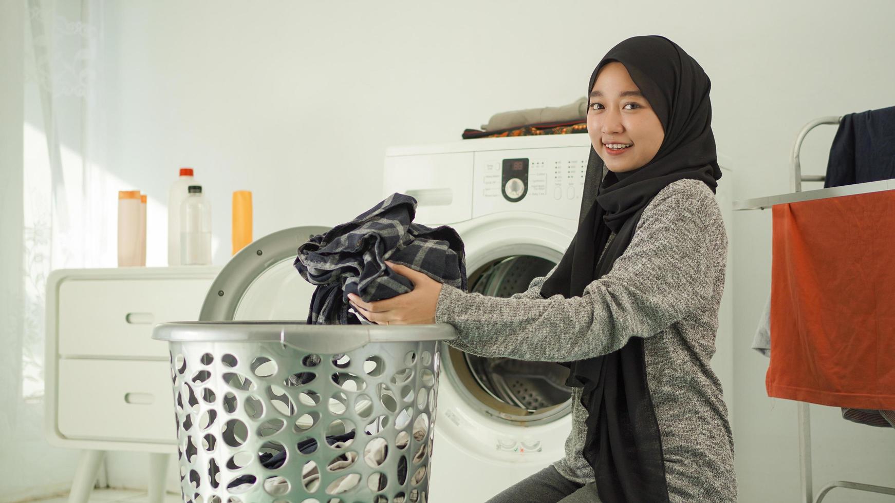 une jeune femme asiatique ramasse des vêtements sales pour les laver à la maison photo