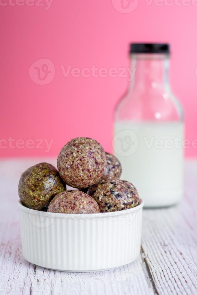 collation saine. boule d'énergie avec prune de date, sésame noir et blanc, chia et rasin dans un bol en céramique sur une table en bois. végétalien végétarien. photo