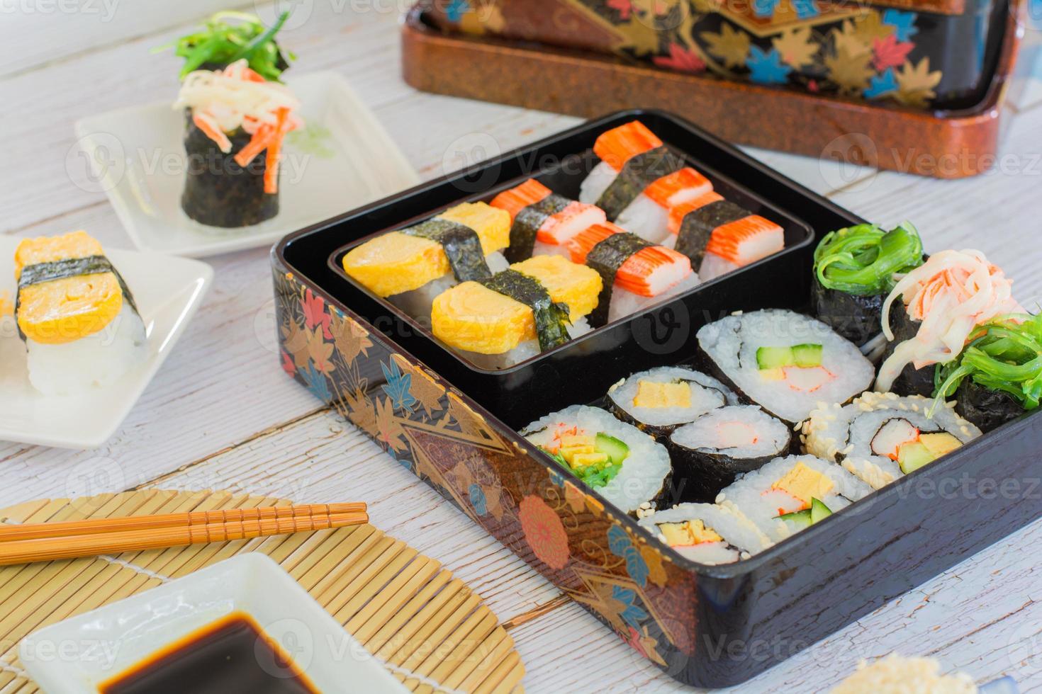 ensemble de sushis variés, tamagoyaki, sushis aux bâtonnets de crabe et makis dans une boîte à bento servis avec sauce soja et wasabi. délicieuse cuisine japonaise. photo