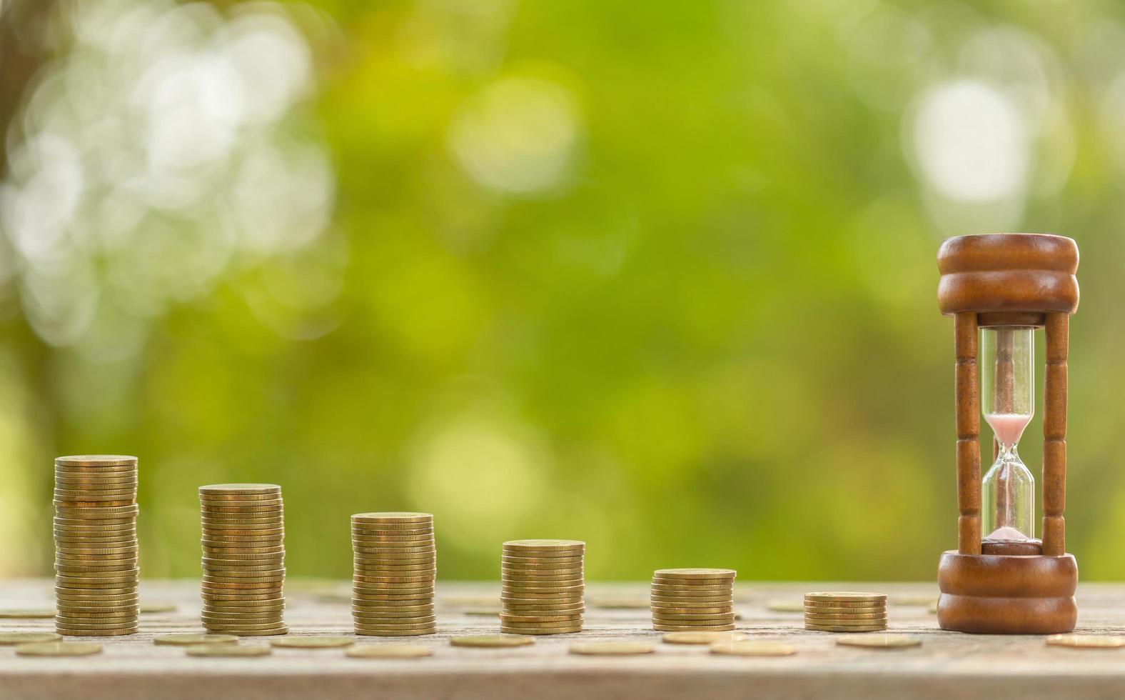 sablier vintage ou sablier et pièce de monnaie sur table en bois. concept d'économie de temps et d'argent photo