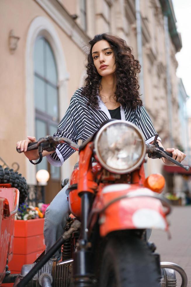 belle jeune femme assise sur une moto dans une rue de la ville photo