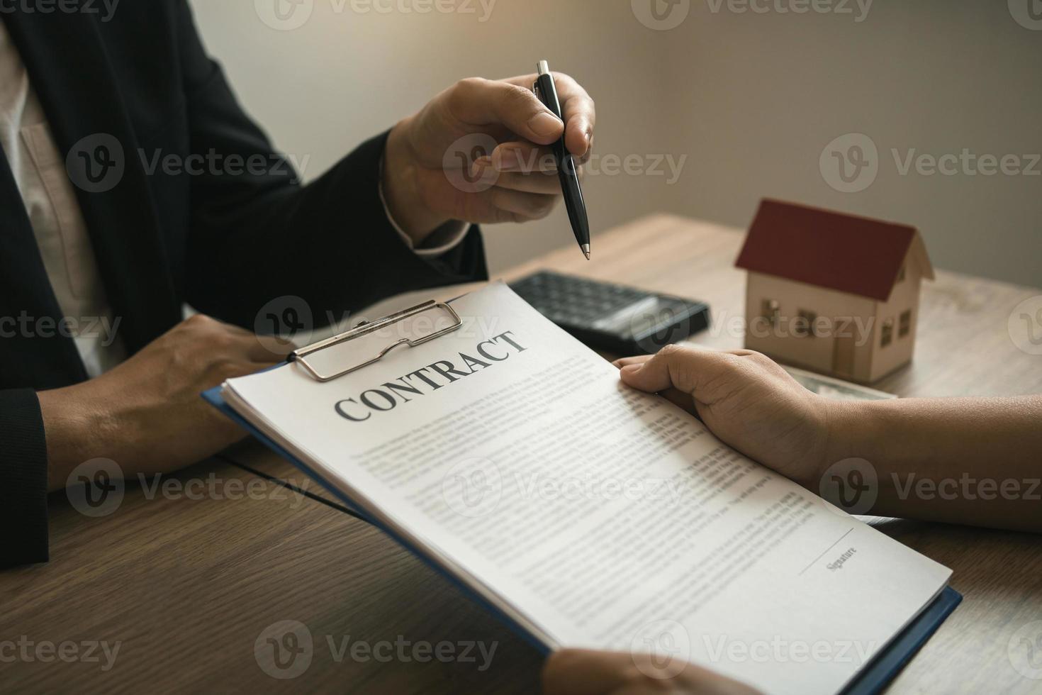des agents à domicile discutant avec des acheteurs de maison qui signent des contrats au bureau. photo