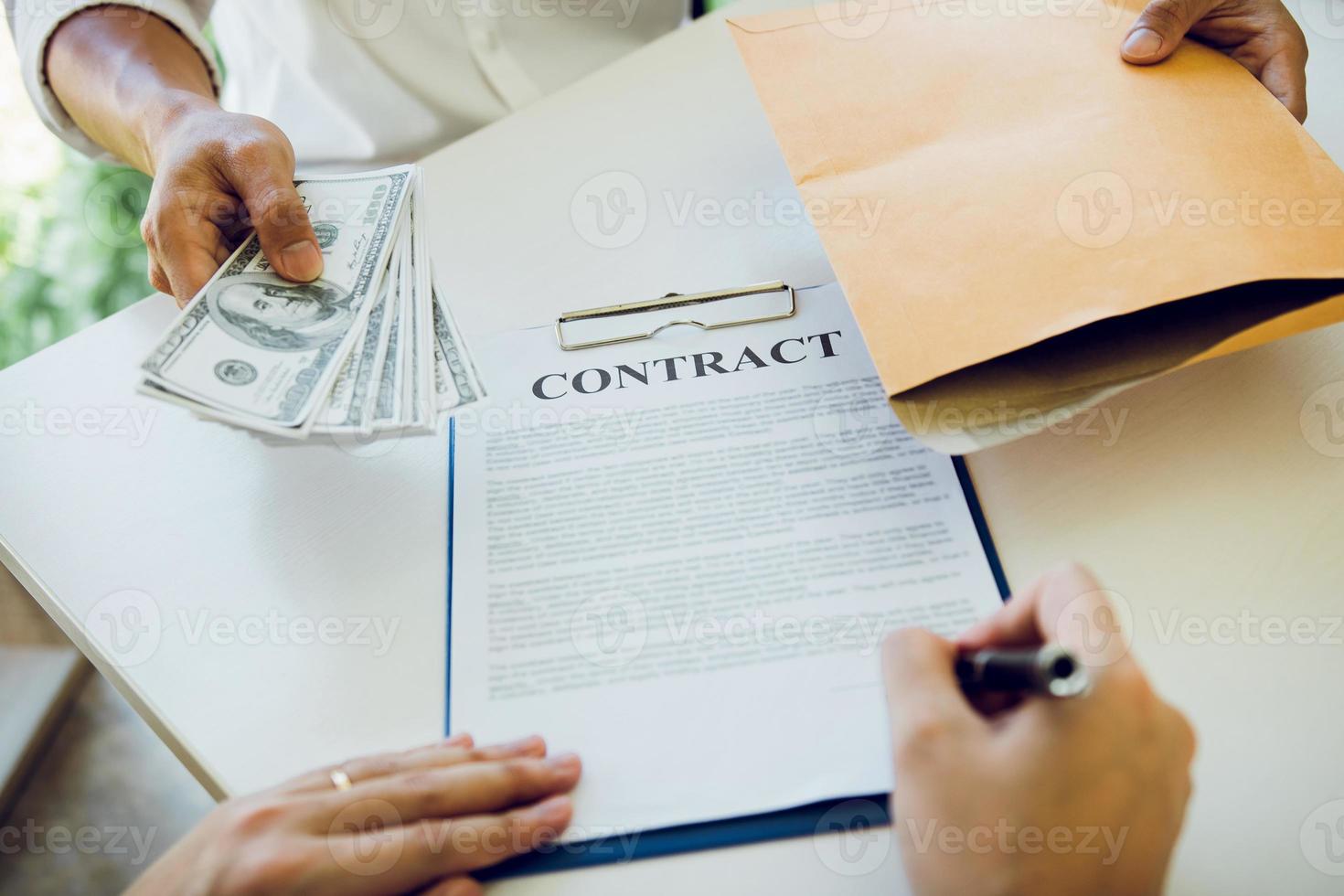 de l'argent entre les mains d'hommes d'affaires qui se soumettent à des entrepreneurs pour forcer la signature de documents contractuels sur le concept de corruption. photo