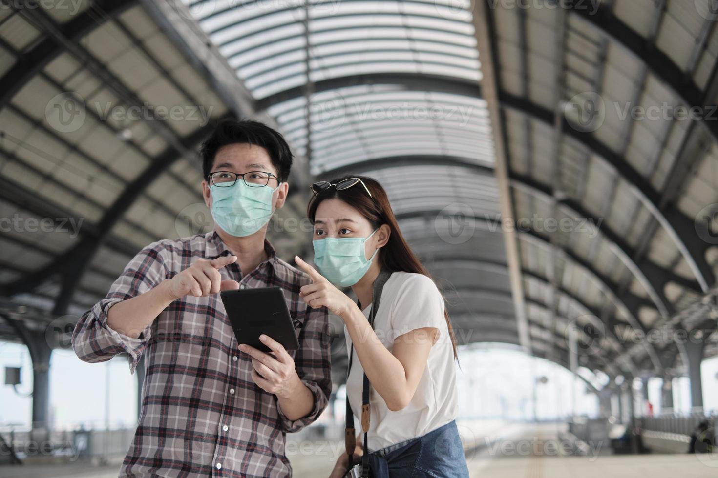 couple de touristes asiatiques avec des masques faciaux rechercher des informations, trouver des lieux de voyage par carte de téléphone portable dans une gare en thaïlande, mode de vie de voyage de passagers, transport occasionnel, vacances de voyage. photo