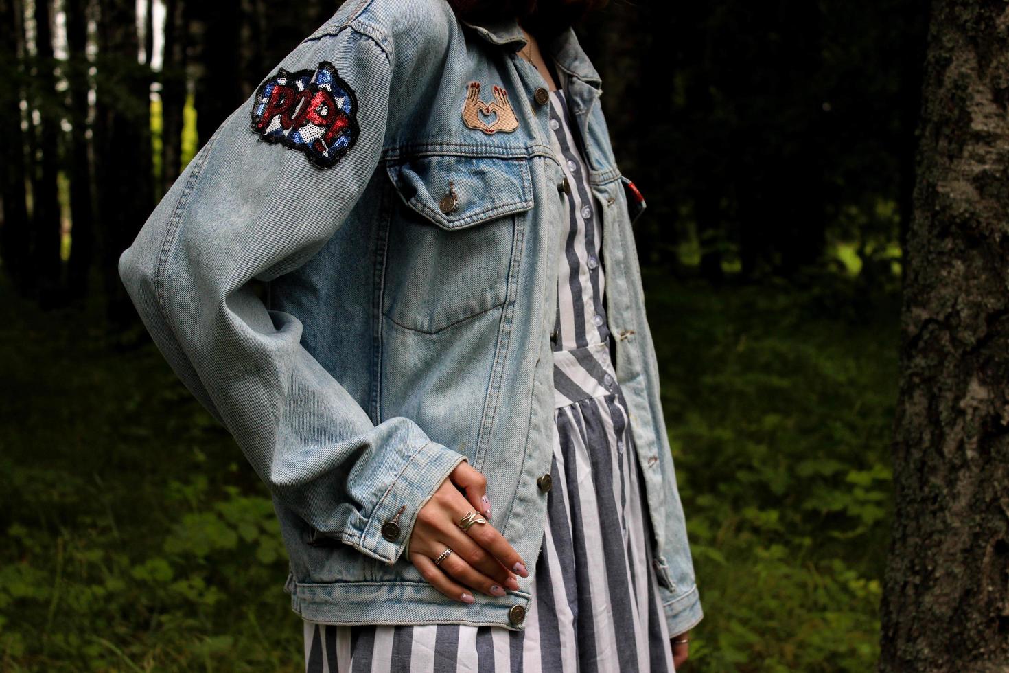 fille en veste en jean et robe rayée en forêt photo