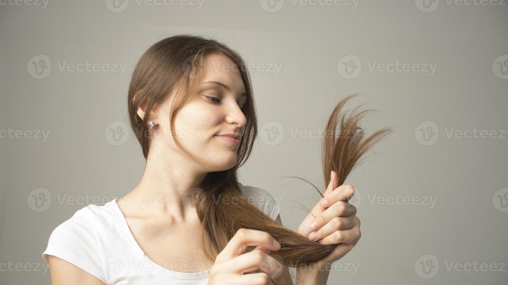 fille sur fond gris tient un cheveu dans sa main photo