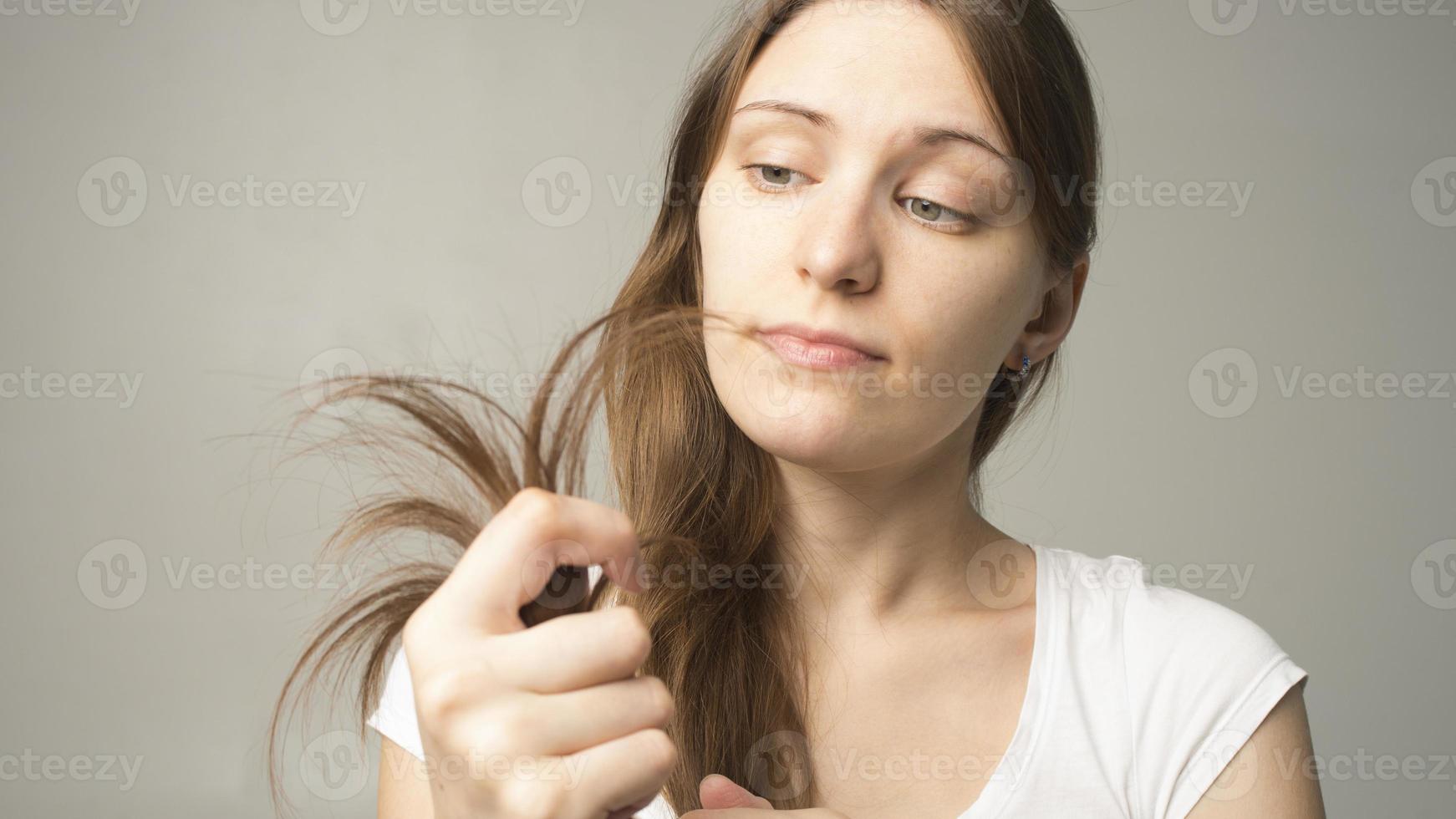 fille sur fond gris tient un cheveu dans sa main photo