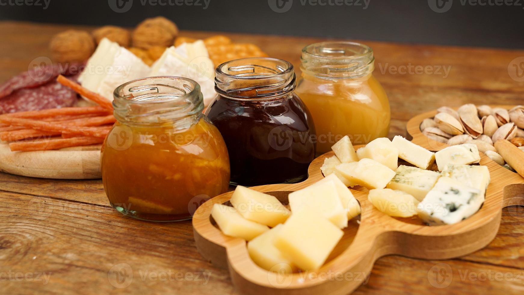 assiette de viande et de fromage pour les apéritifs. pots de confiture et de miel. photo