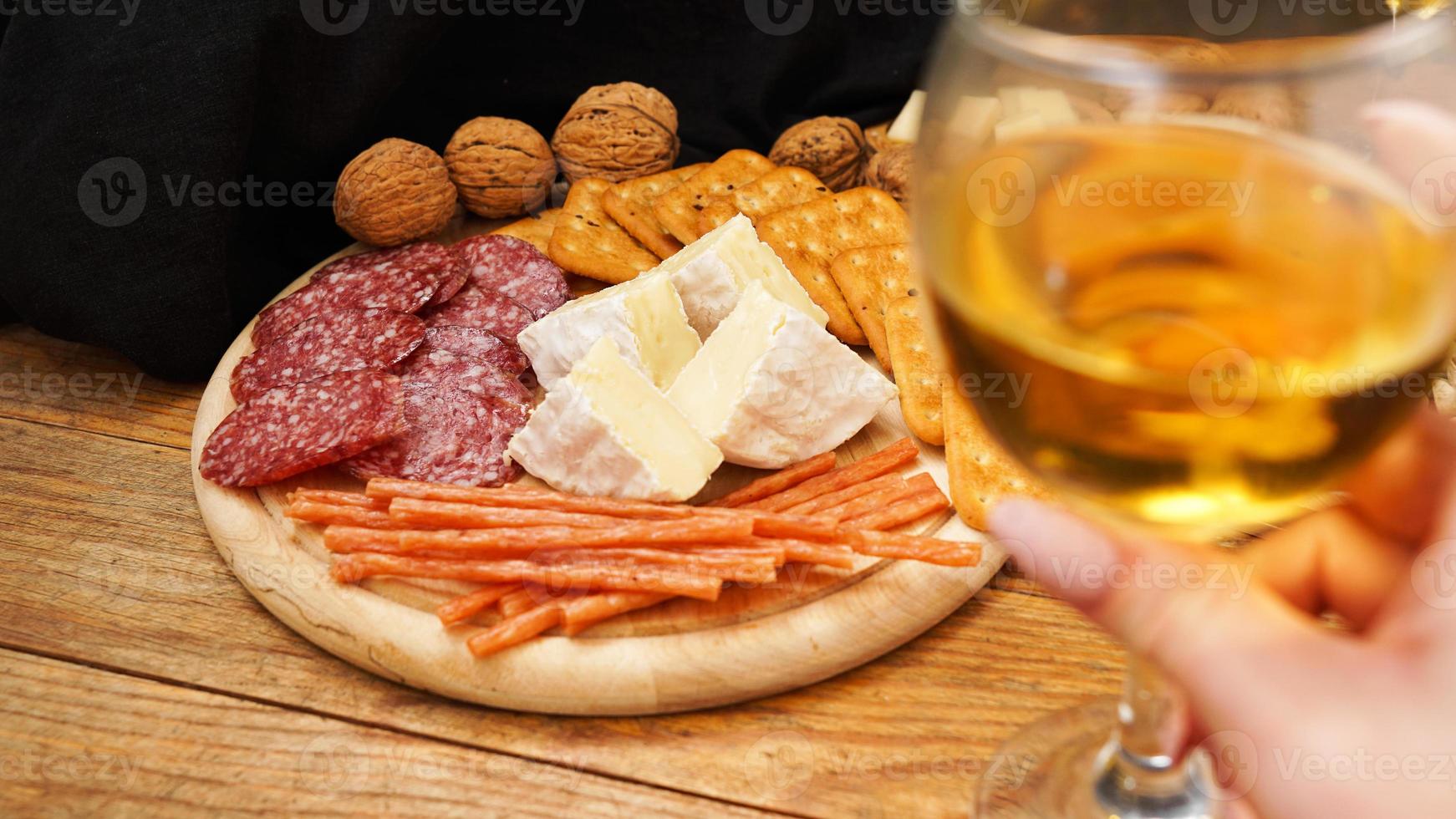 premier plan flou avec la main tenant un verre de vin. plateau de fromages et viandes photo