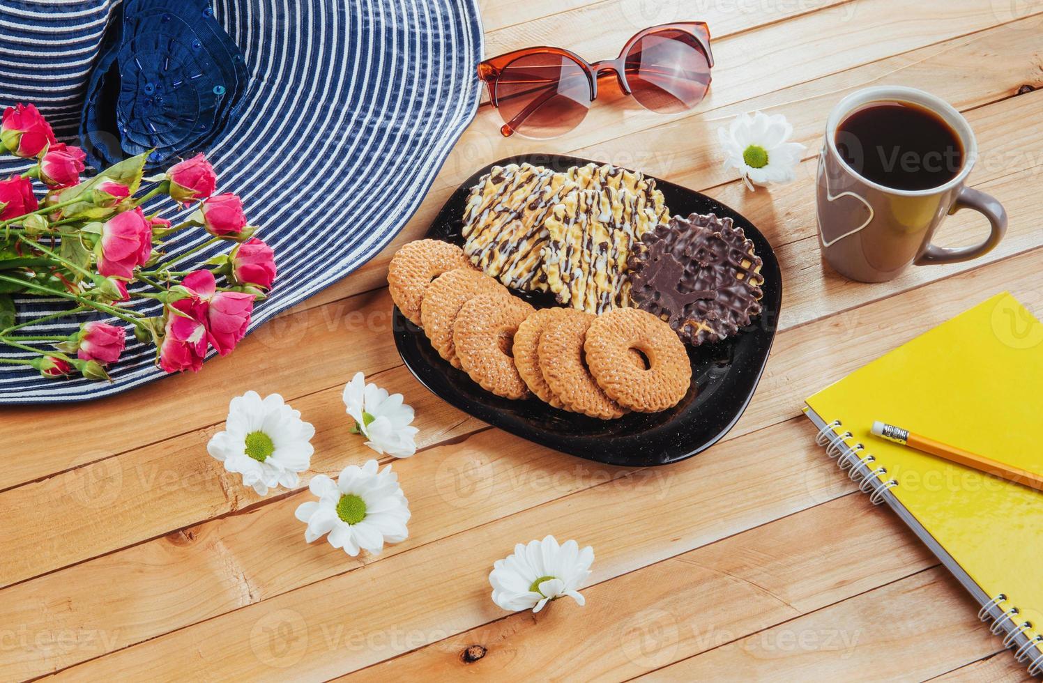 le café expresso se dresse sur une table en bois avec des biscuits, un bloc-notes et un crayon. photo