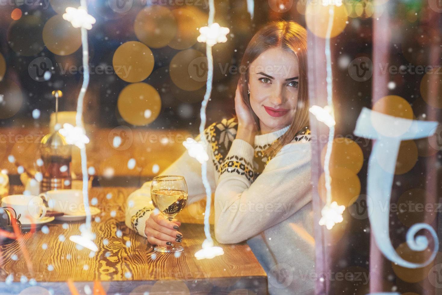 belle jeune femme assise dans un café, buvant du vin. noël, nouvel an, saint valentin, concept de vacances d'hiver photo