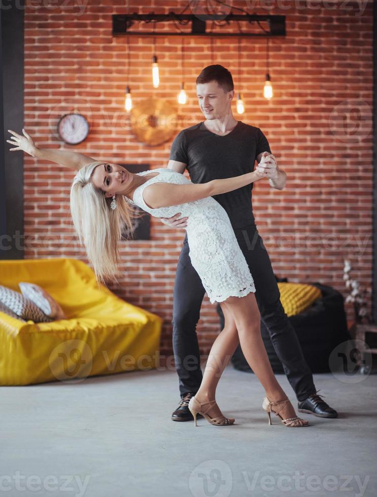 jeune couple dansant de la musique latine. bachata, mérengue, salsa. deux poses d'élégance sur un café aux murs de briques photo