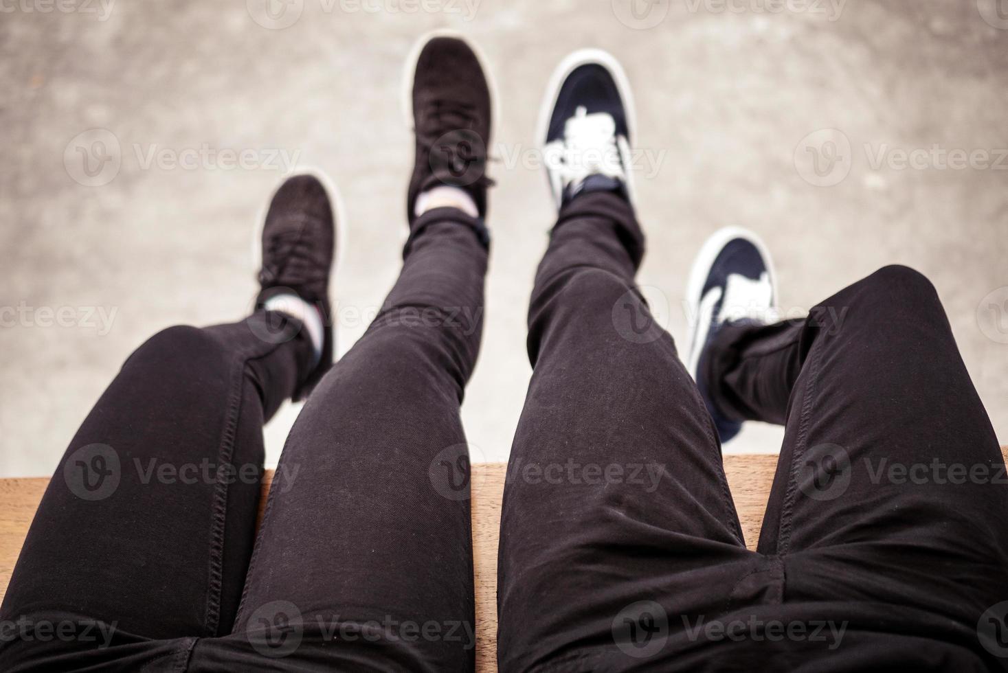 jambe de couple portant un pantalon noir assis avec les jambes suspendues au sol photo