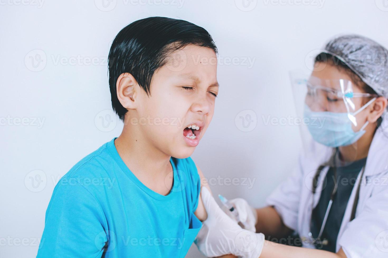 garçon patient avec expression de douleur lors de l'injection de vaccin, phobie des injections. concept de médecine, de vaccination, d'immunisation et de soins de santé photo