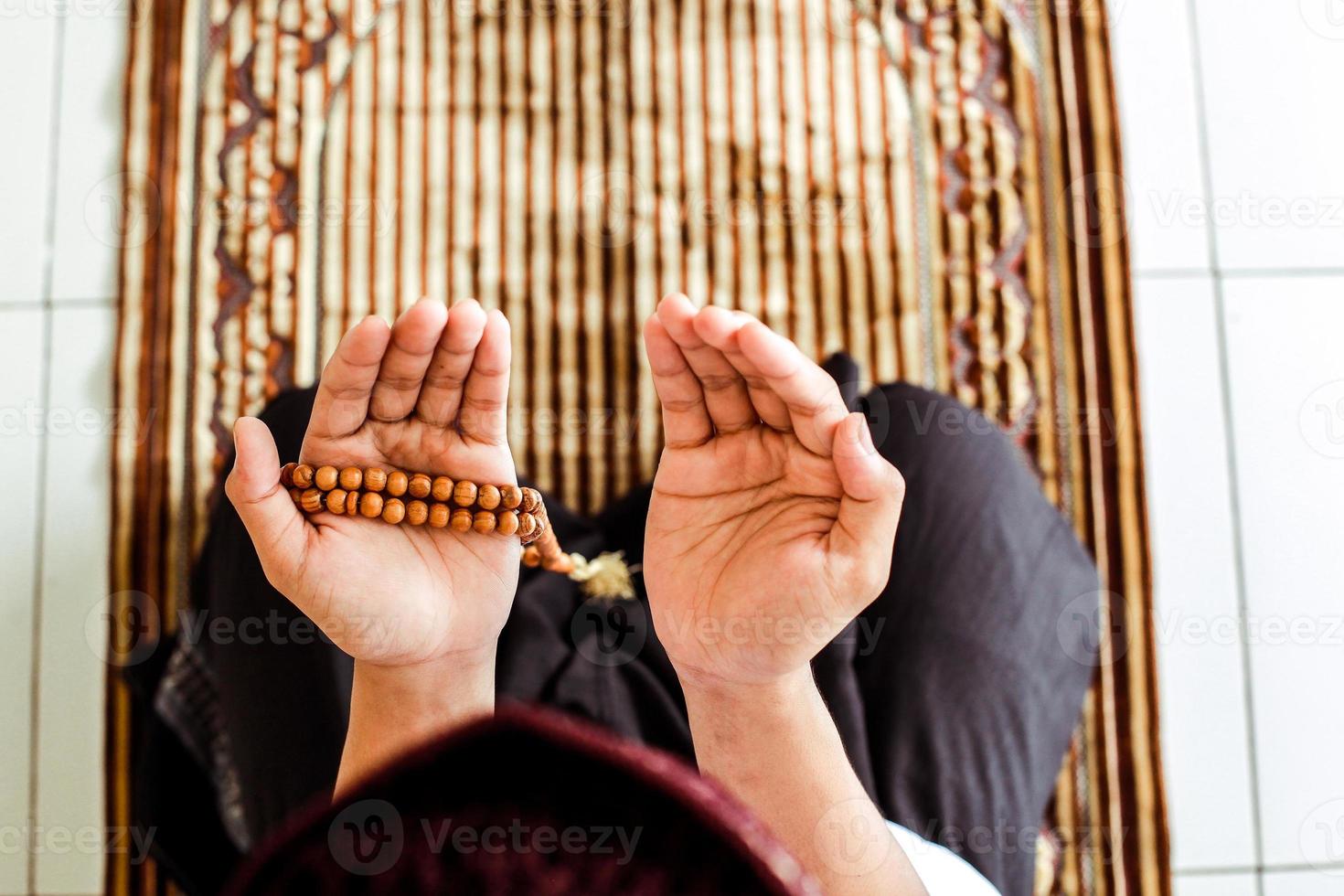 vue de dessus de l'homme musulman avec la main en prière sur le tapis de prière tout en tenant le chapelet photo