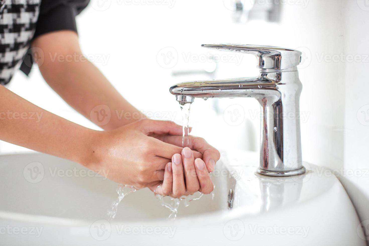 se laver les mains sur un évier blanc avec de l'eau du robinet argentée photo