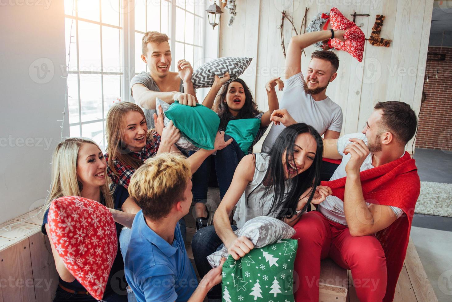 jeunes meilleurs amis fous combattant des oreillers à la maison. groupe de personnes de race mixte. concept de divertissement et de style de vie photo