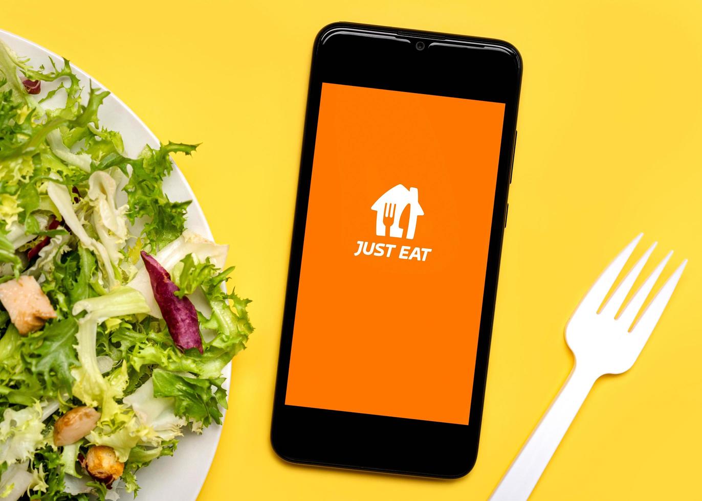 il suffit de manger l'icône de l'application sur l'écran noir du smartphone avec une assiette de salade de laitue et une fourchette en plastique blanc photo