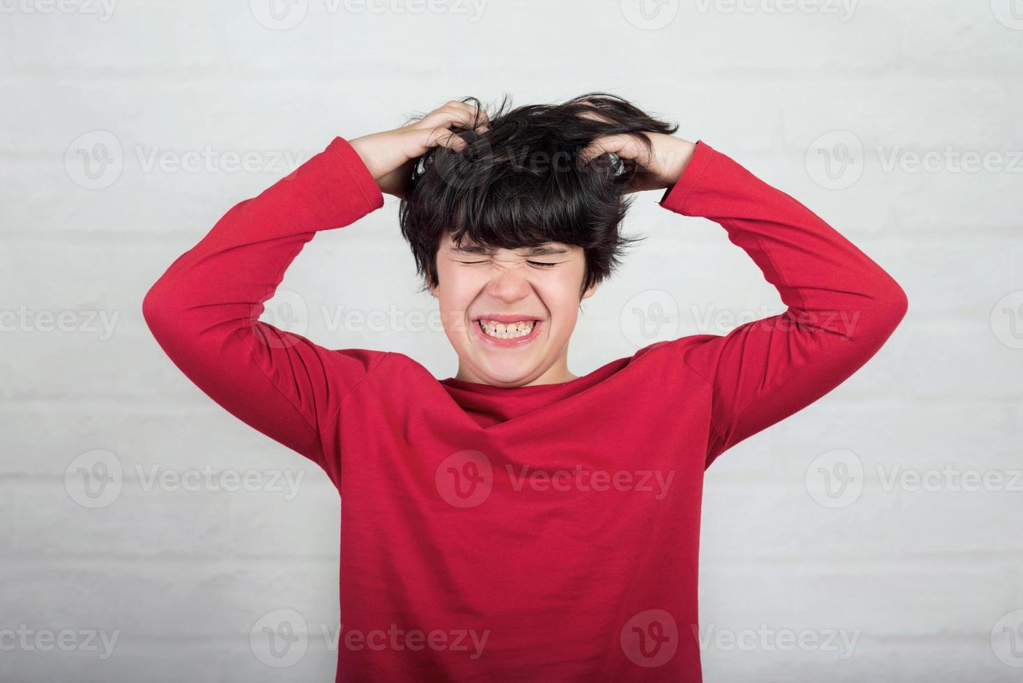 garçon se gratte les cheveux pour les poux de tête photo