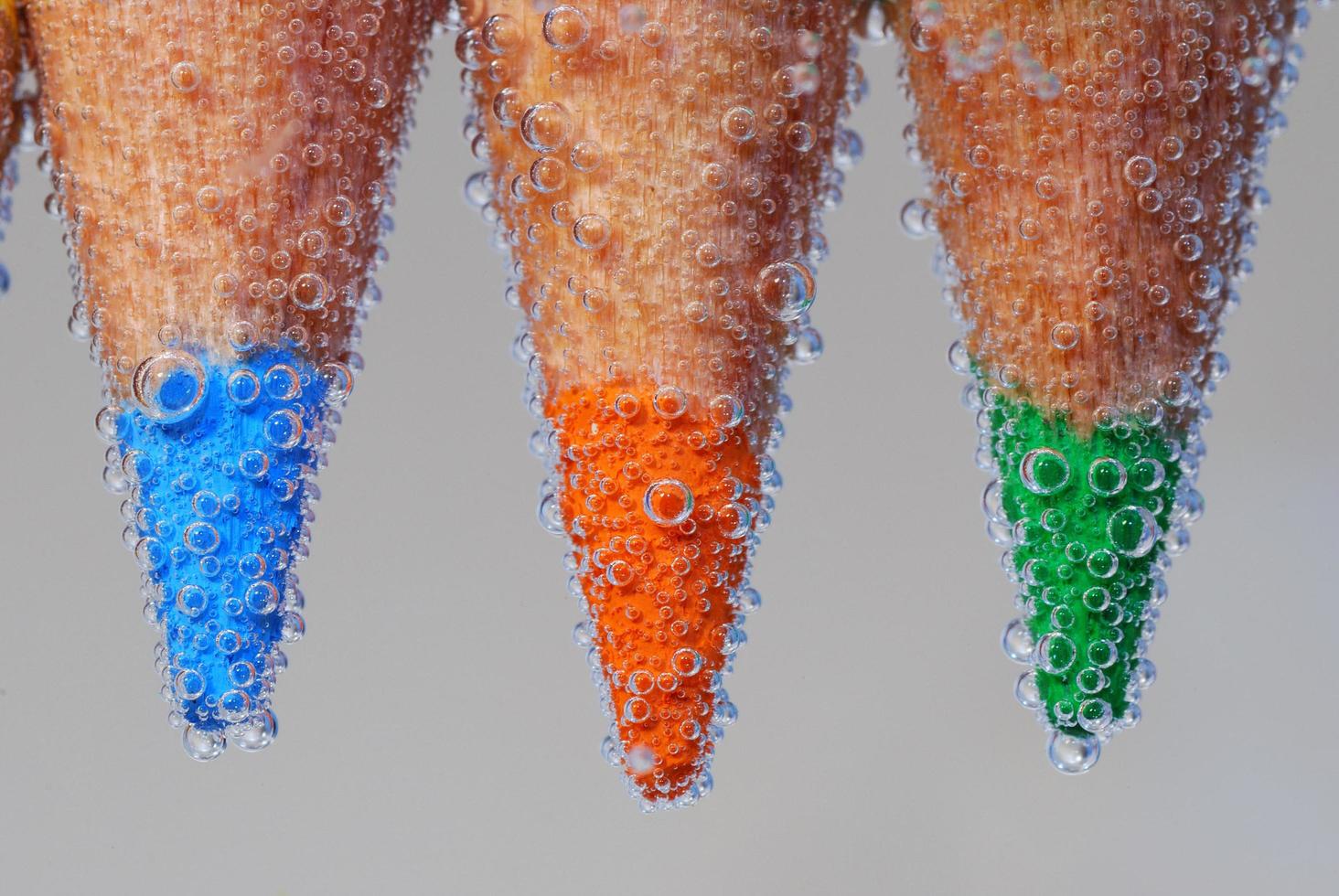 trois crayons de couleur avec des pointes dans l'eau et beaucoup de bulles d'air bleu orange photo