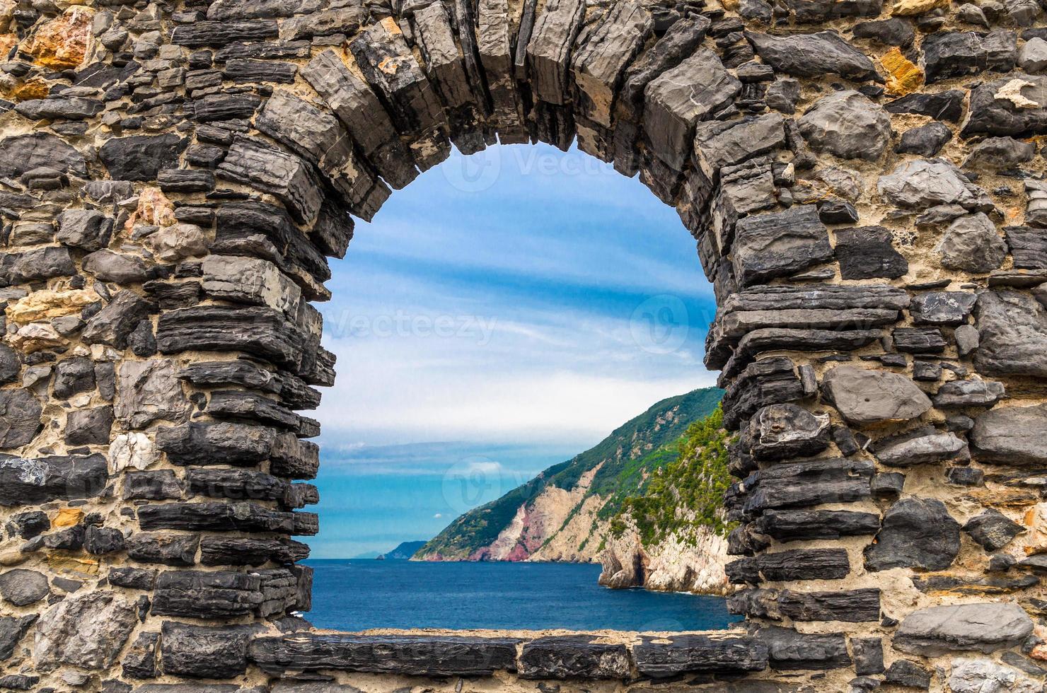 Grotta di lord byron avec eau bleue et côte avec falaise rocheuse à travers la fenêtre du mur de pierre, ville de portovenere photo