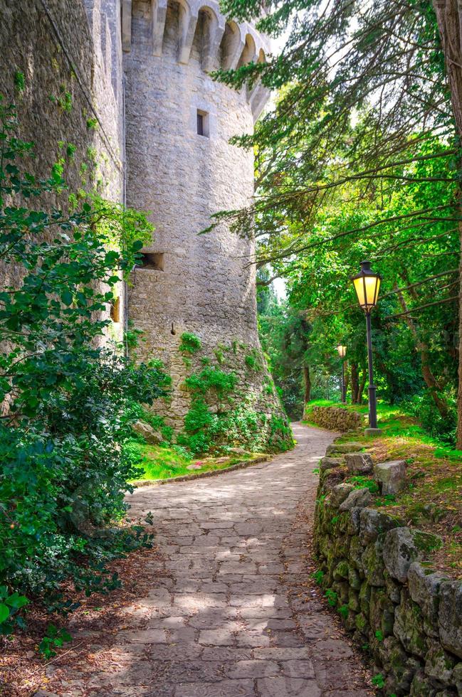 chemin pavé avec lampe de réverbère près du mur de la tour du château médiéval en brique de pierre photo