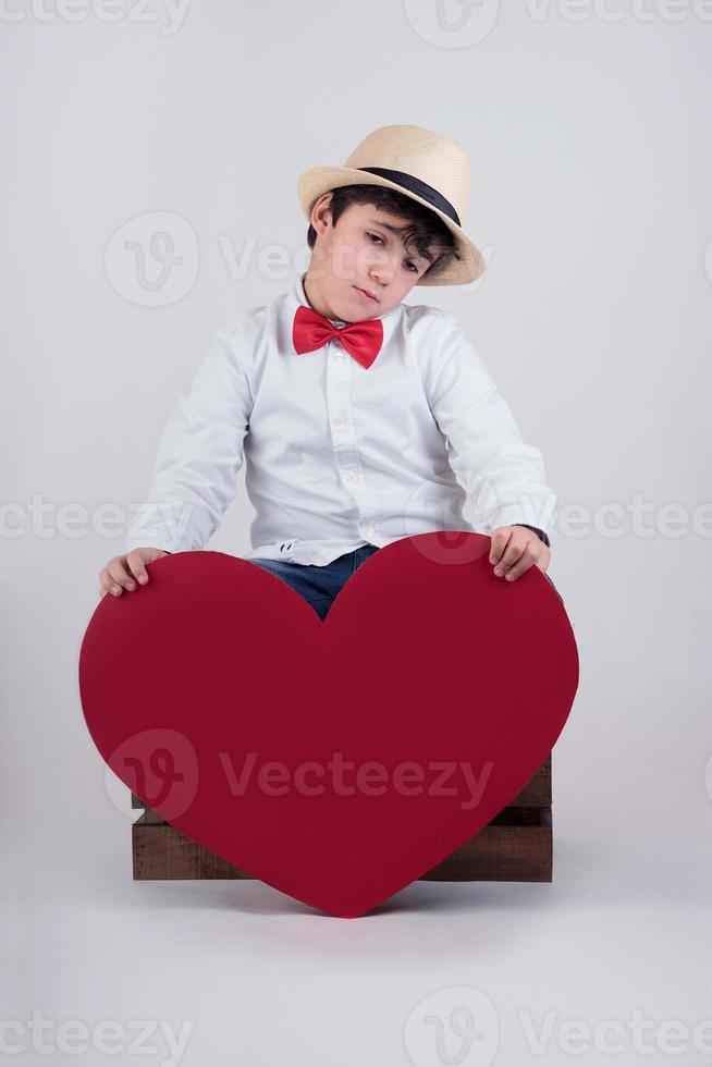 enfant pensif avec un coeur rouge photo