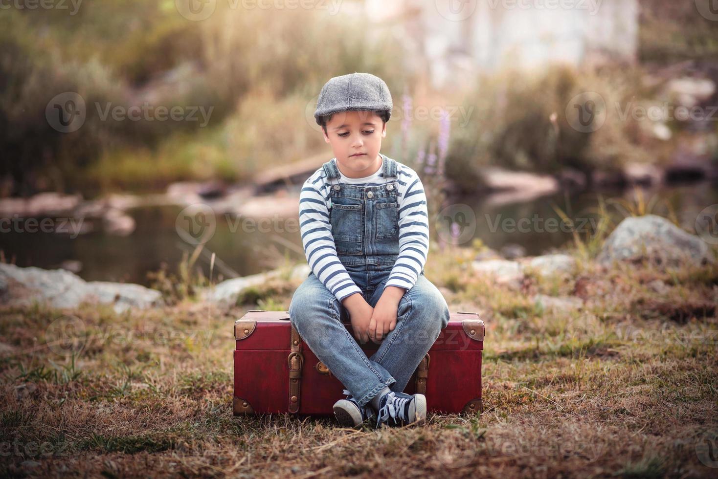 enfant triste assis dans une valise photo