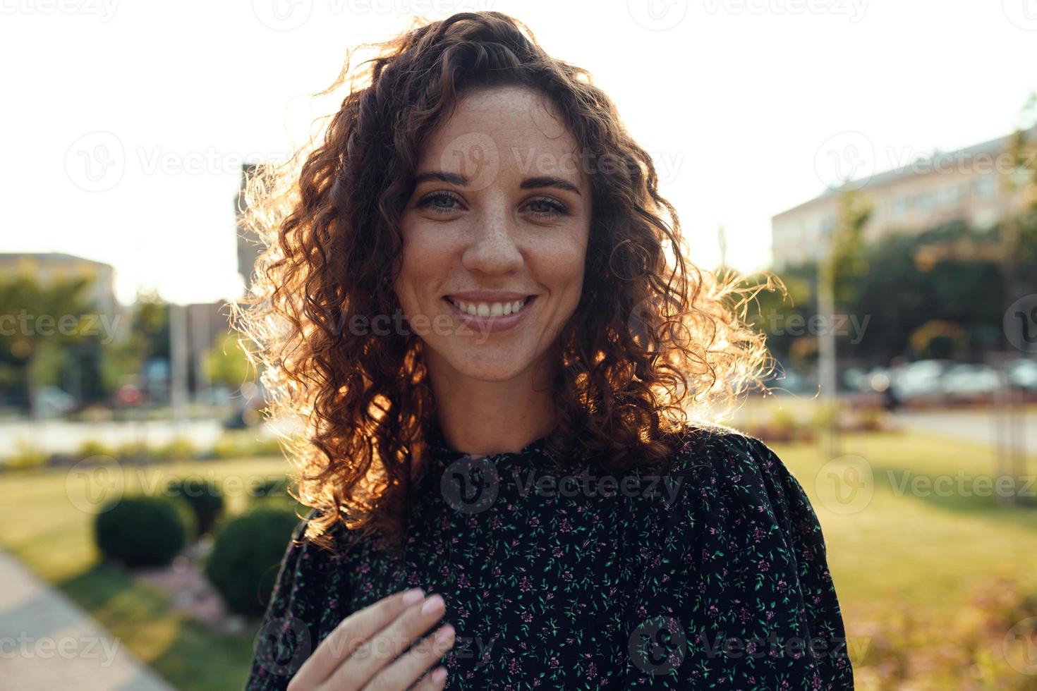 portraits d'une charmante fille rousse avec des taches de rousseur et un joli visage. la jeune fille pose pour la caméra dans le centre-ville. elle a une bonne humeur et un doux sourire photo