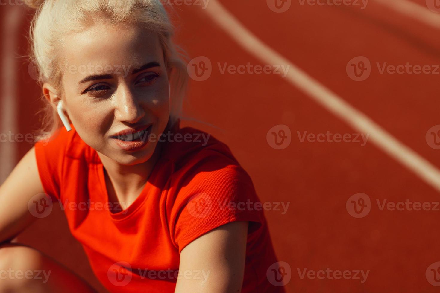 portrait en gros plan d'une belle blonde assise sur une piste de jogging photo