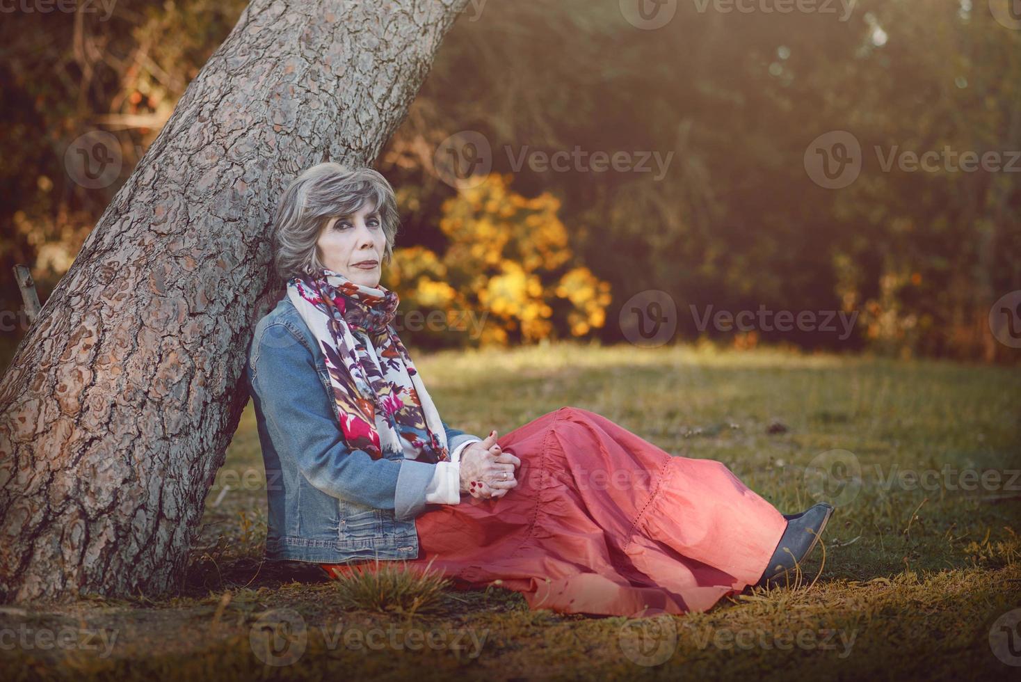 heureuse femme âgée assise sur l'herbe photo