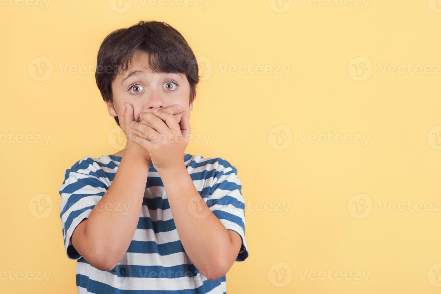 enfant couvrant sa bouche par les mains photo