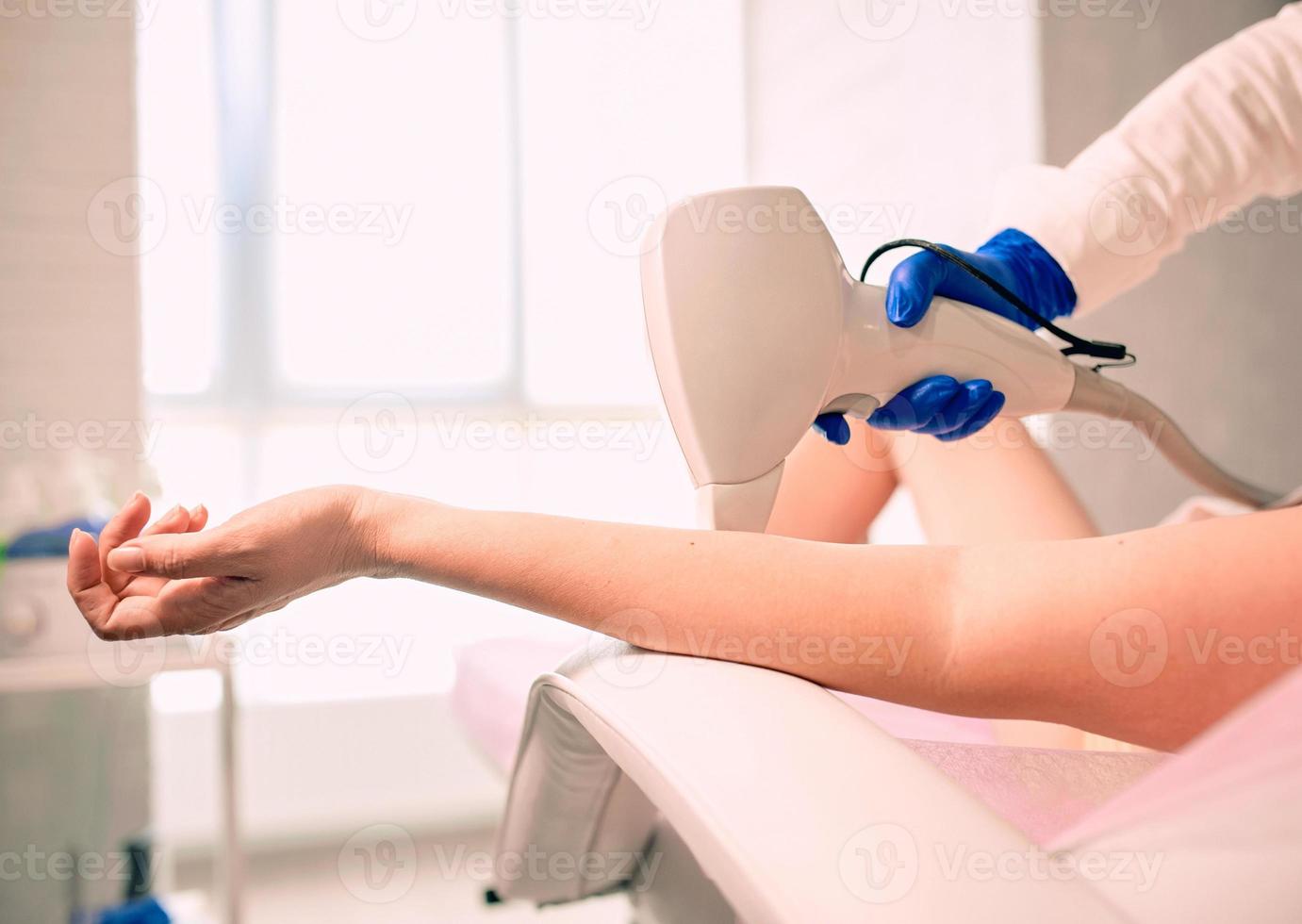 main de femme lisse pendant l'épilation au laser sur fond de bureau de cosmétologues. beauté, traitement, concept d'épilation photo