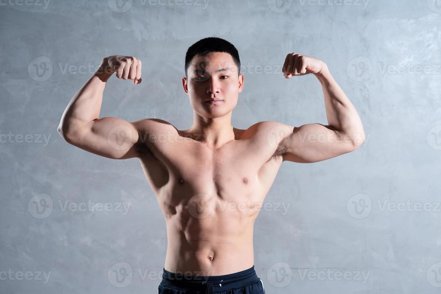 homme asiatique musclé posant sur fond gris photo