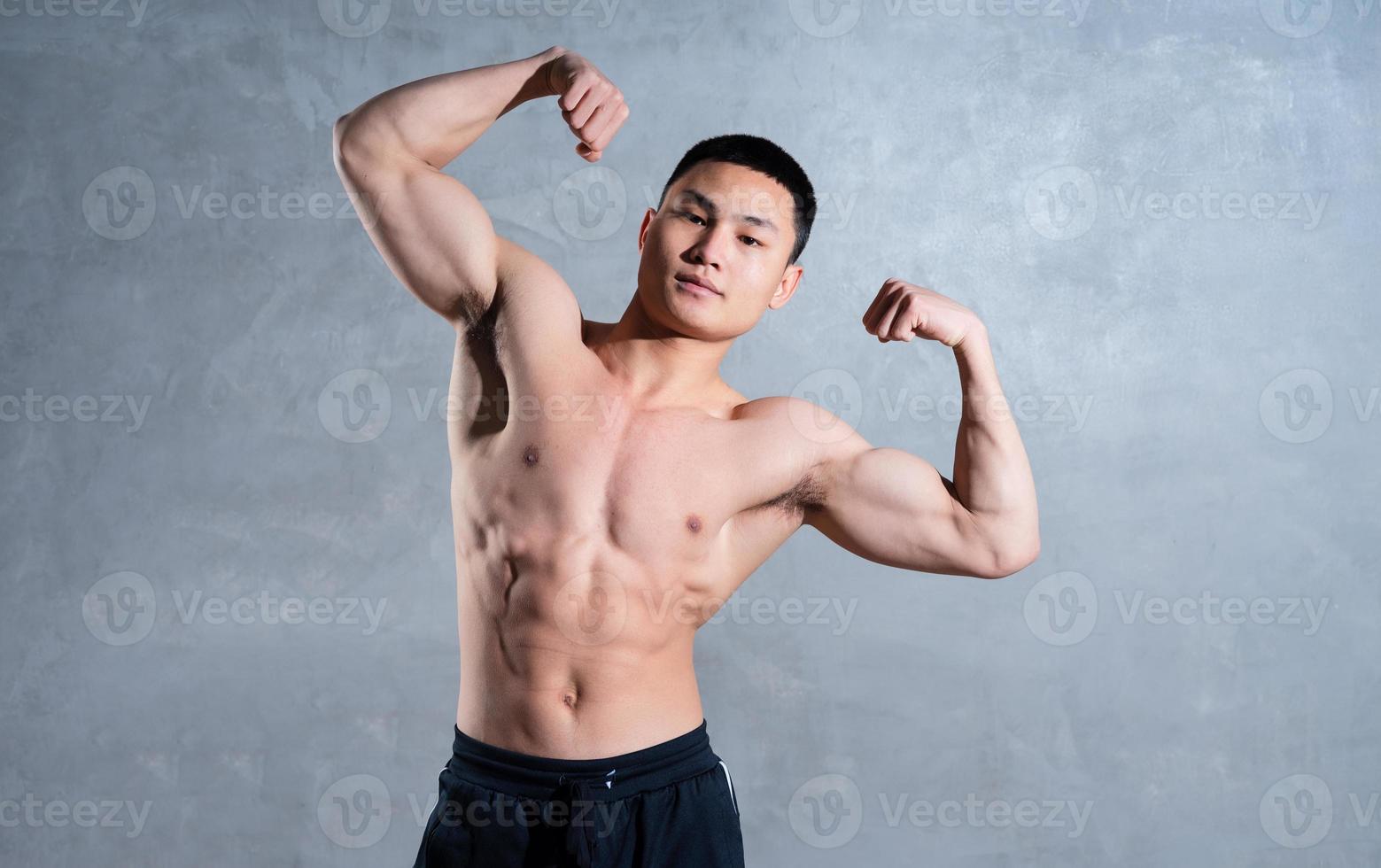 homme asiatique musclé posant sur fond gris photo