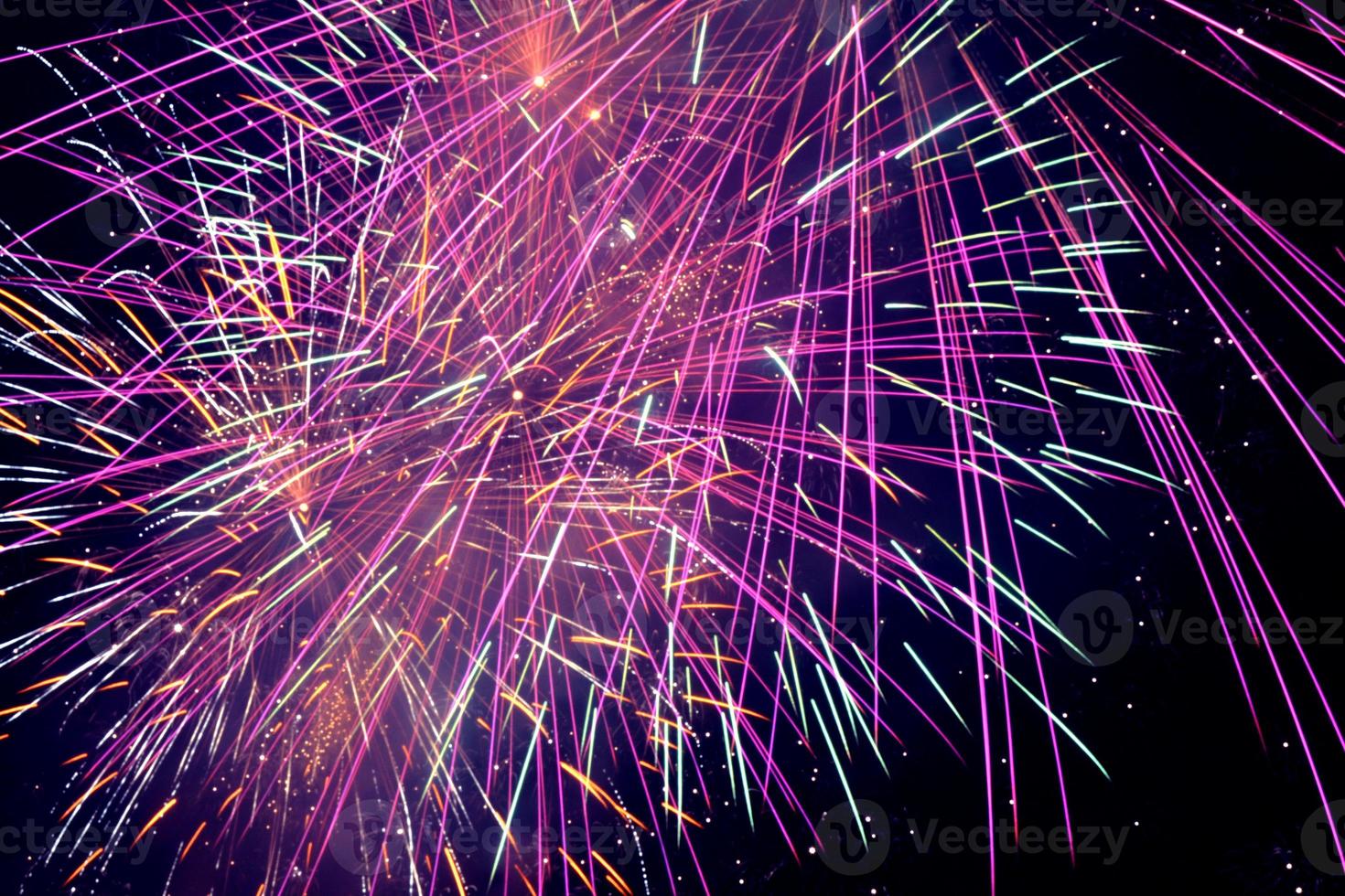 feux d'artifice violets dans un ciel sombre. pétard festif violet. feu d'artifice violet, rose et orange vif dans le ciel nocturne. feu d'artifice violet et bleu dans le ciel nocturne. photo