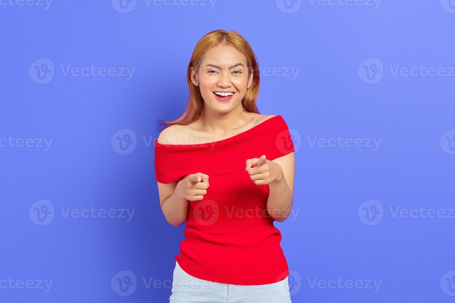 Portrait of attractive young asian woman with blonde hair standing doigt pointé devant isolé sur fond violet photo