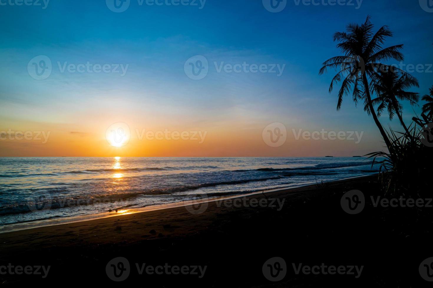 coucher de soleil sur la plage tropicale avec palmier et ciel coloré photo