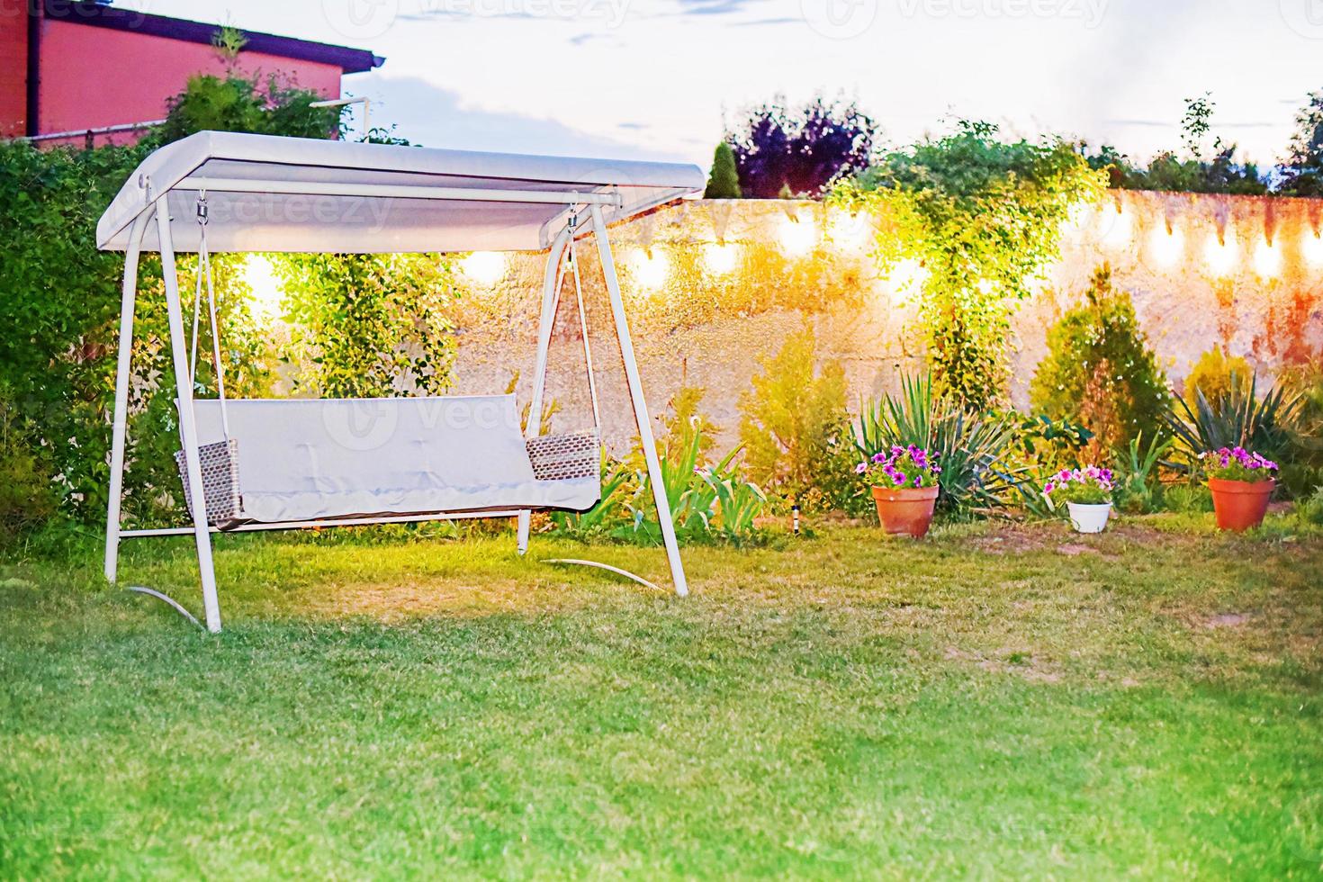jardin triple balançoire dans l'éclairage du soir. parcelle d'été dans le jardin pour la détente. photo