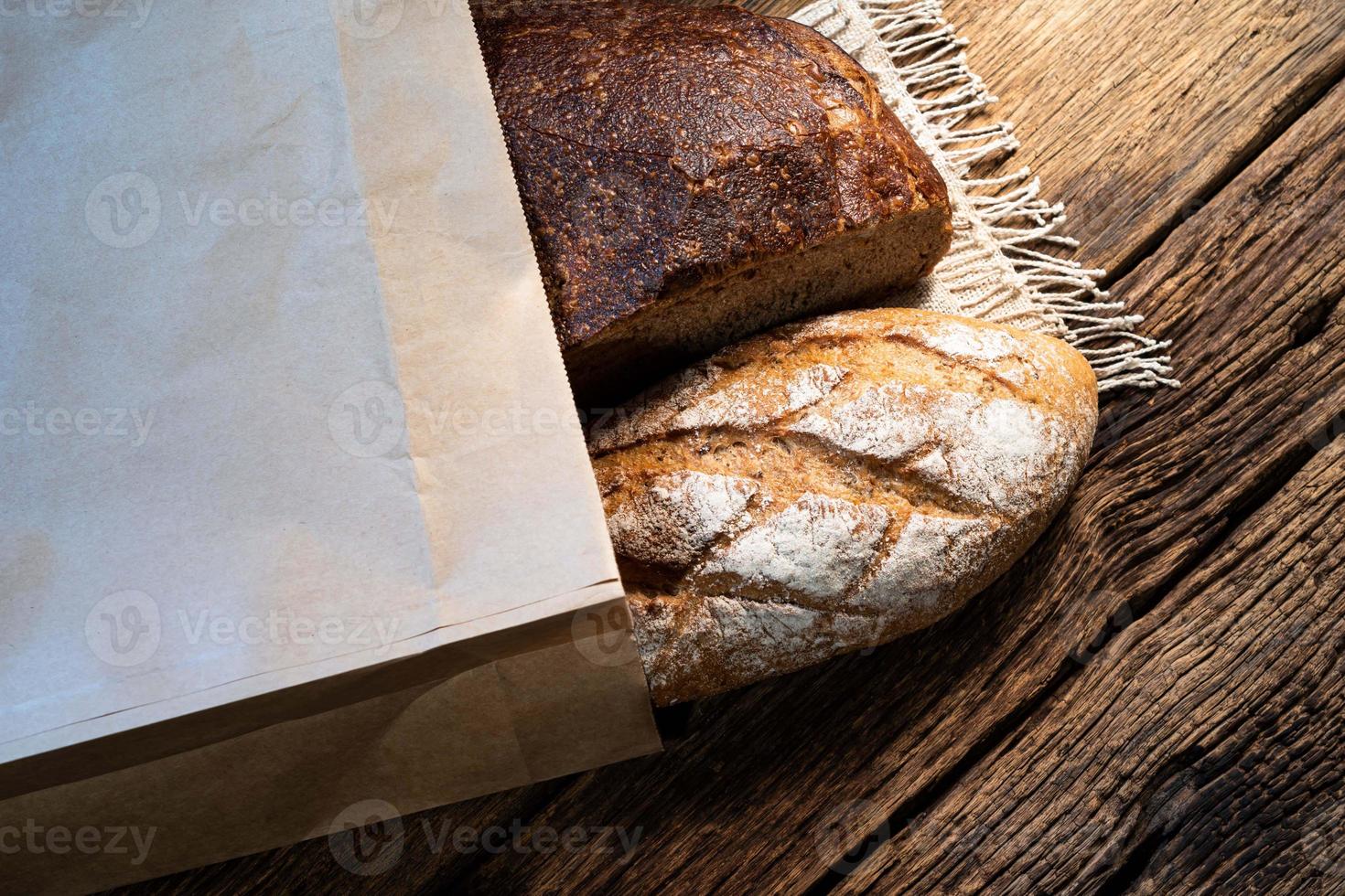 pain de seigle différent et baguette en sac isolé sur fond de bois. photo