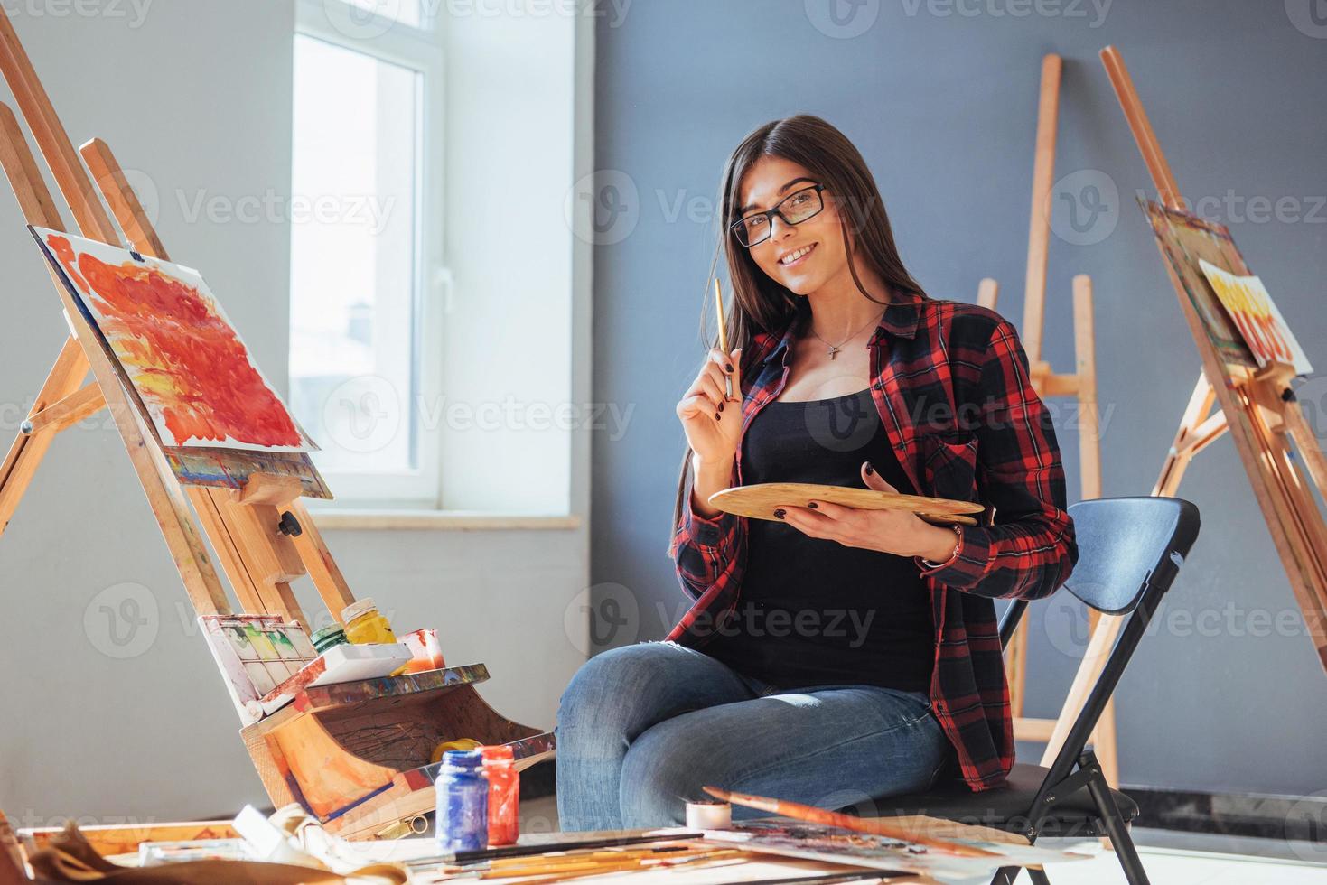 artiste aux cheveux noirs tenant un pinceau à la main et dessine une image sur toile. pense que tirer sur photo