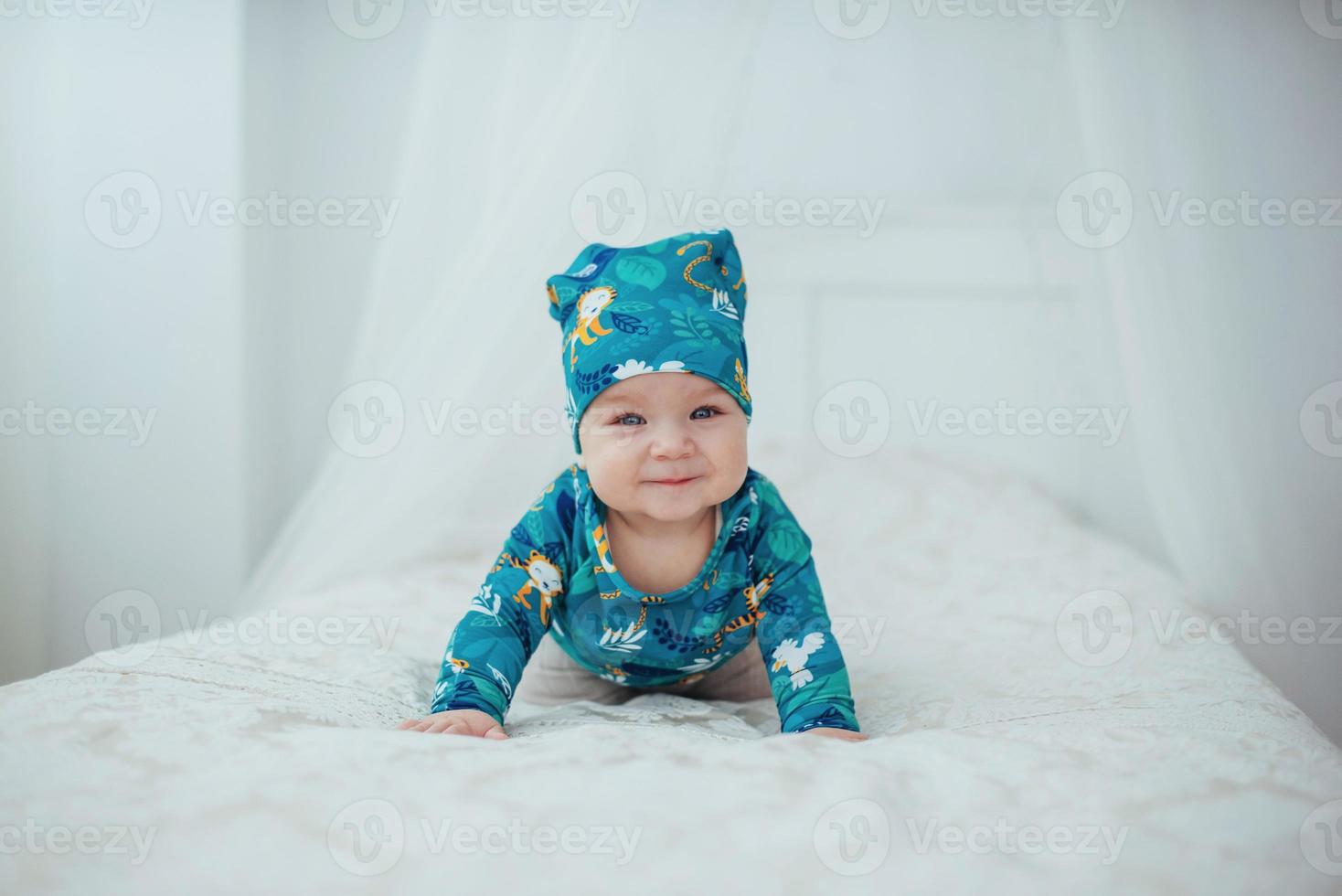 bébé nouveau-né vêtu d'un costume vert allongé sur un lit moelleux dans un studio blanc. photo